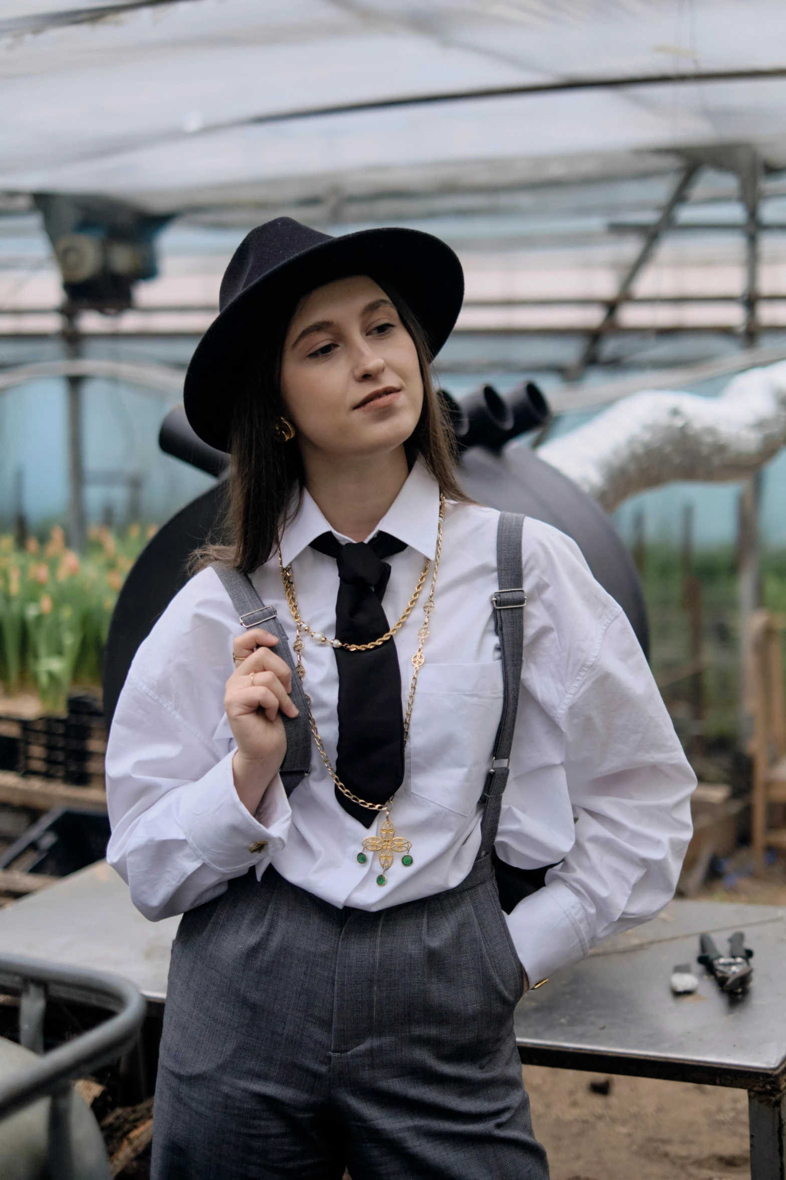 a young lady wearing overalls and a hat poses for the camera