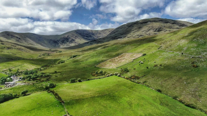 two hills surrounded by green grass and rolling clouds