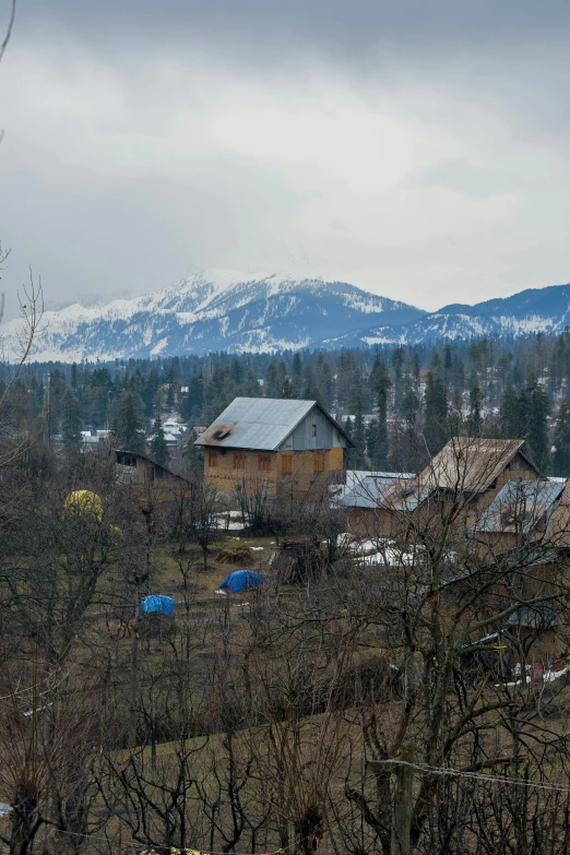 an old farm with snow on the mountains