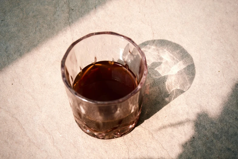 a wine glass filled with brown liquid on the floor