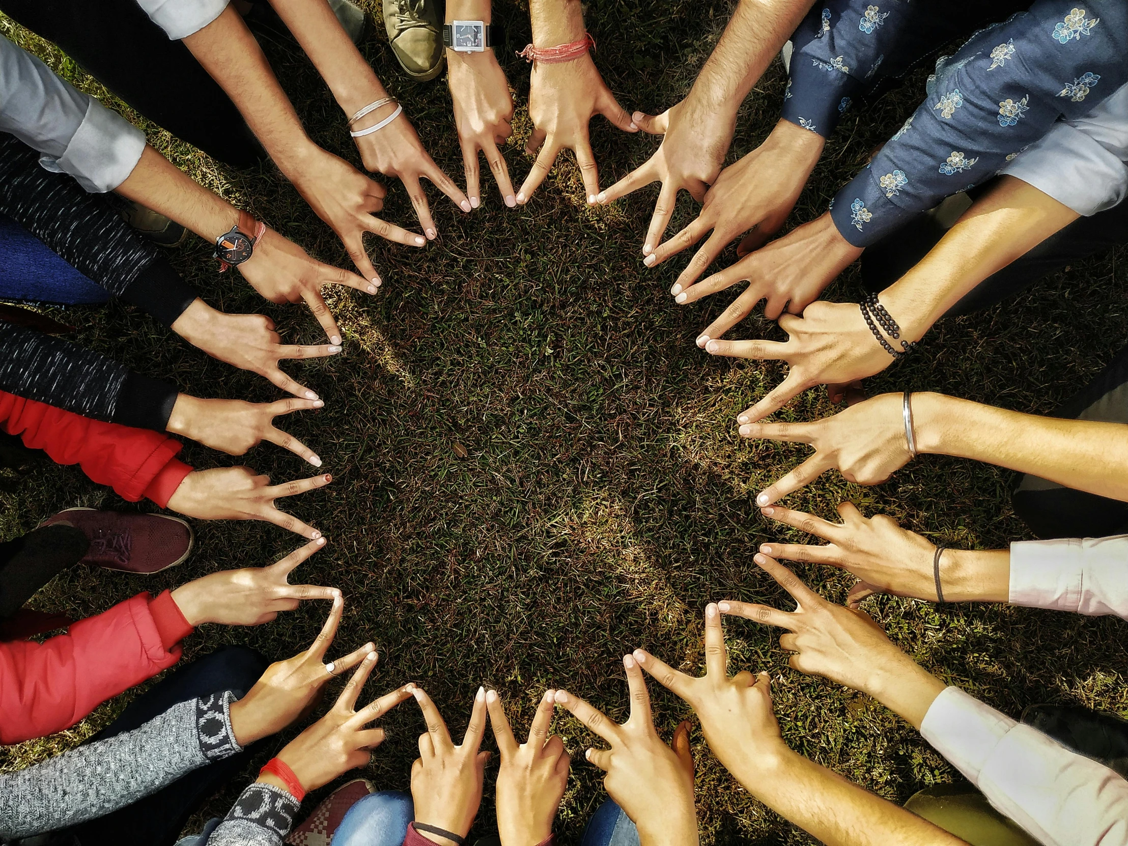 a circle of people's hands together with the middle pointing up