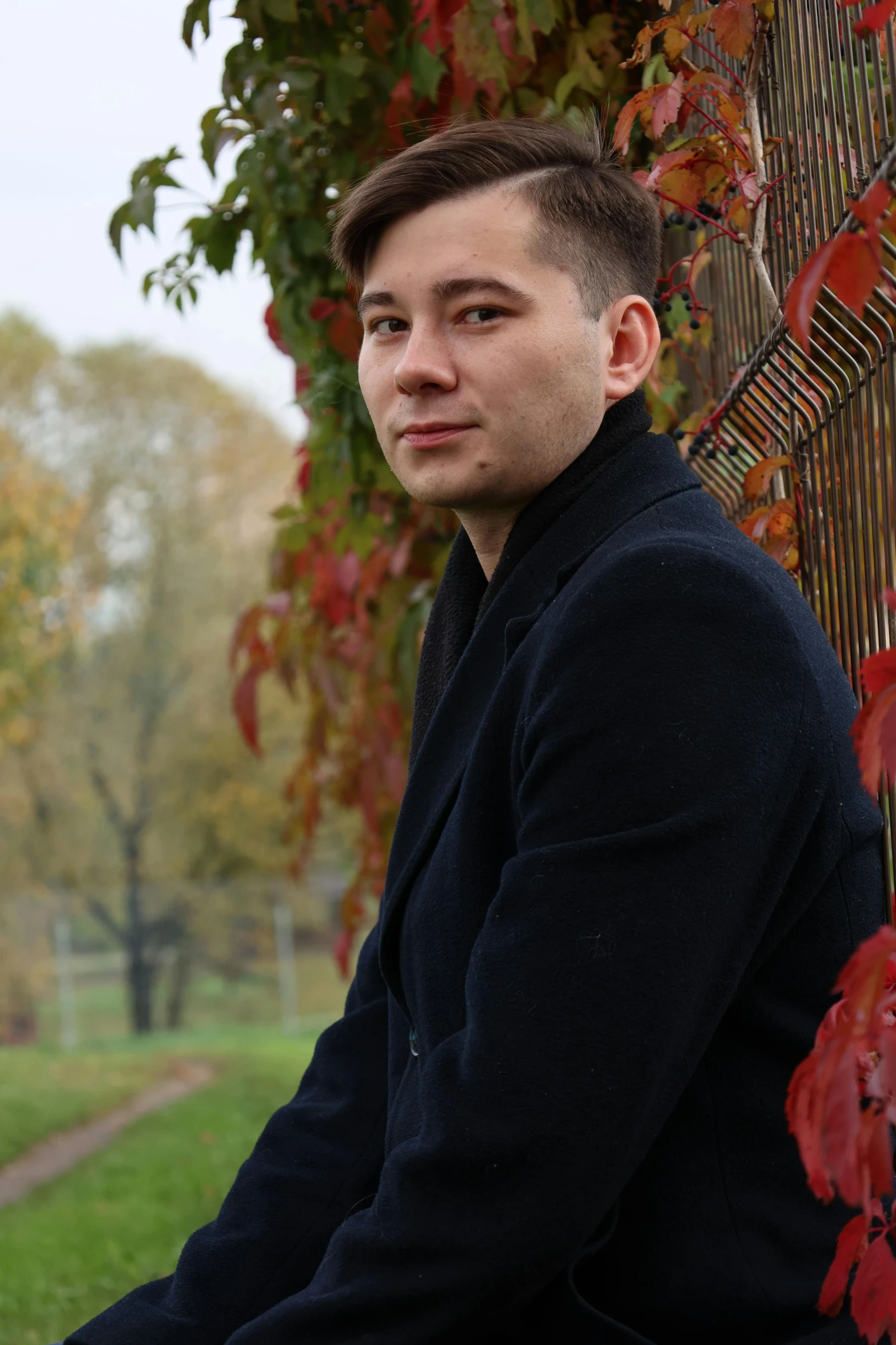 a man sitting on a fence next to a lush green field