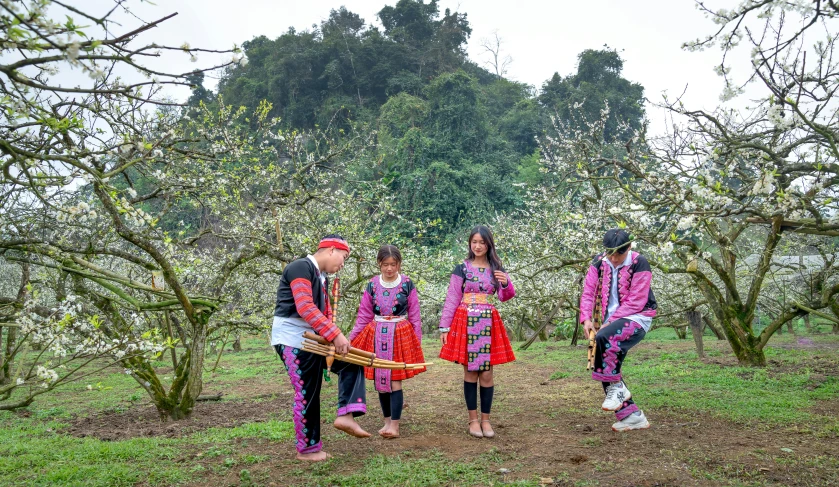 five people dressed in matching clothes standing near trees