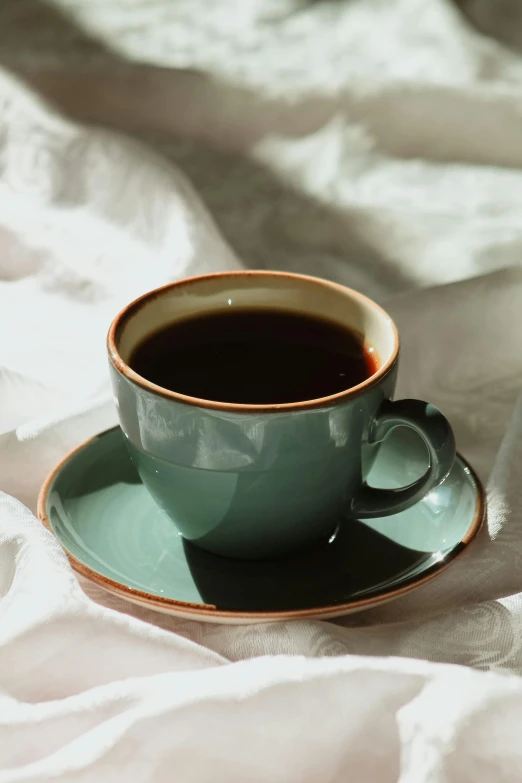 a cup of tea and saucer sitting on white sheet