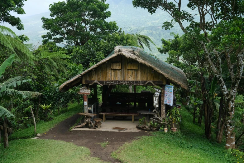 small wooden structure in front of lots of trees with a sign in the center