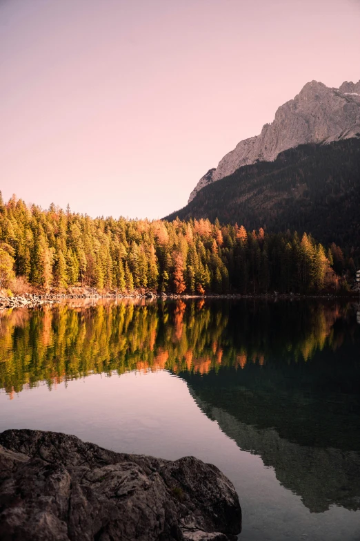 the sun shines on a calm lake near a forest