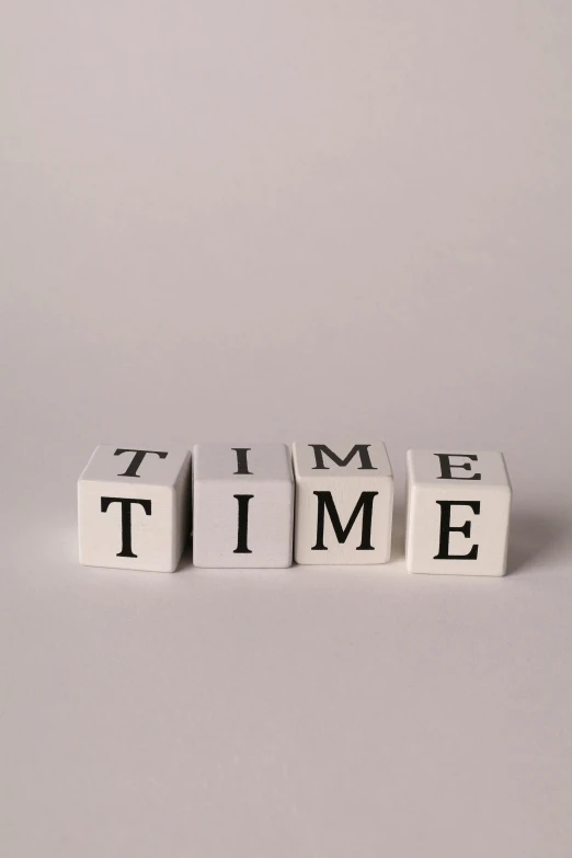three cubes shaped to spell time, with letters on each