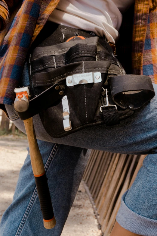 a man wearing blue jeans is holding a bag and a baseball bat