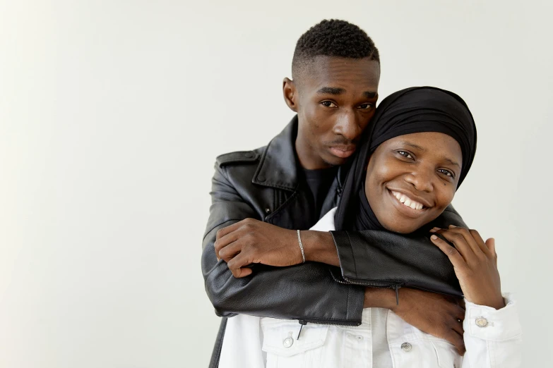 two people, one wearing a black head scarf and one in a white shirt, are emcing