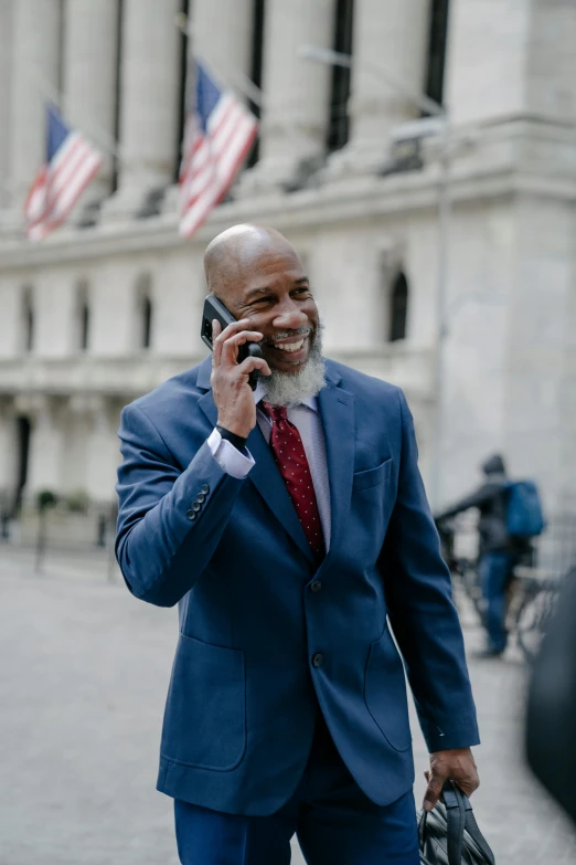 a bearded man in a suit talking on his cell phone