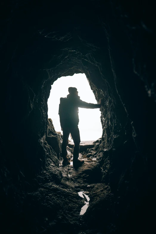 a person standing in a tunnel with a light coming in