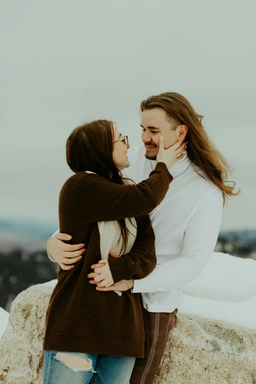 a woman hugging a man with long hair