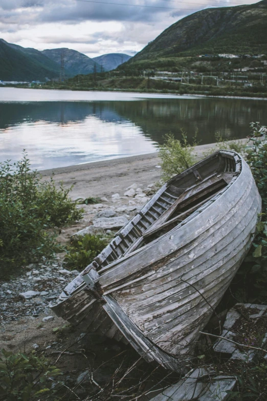 a small boat sits on the shore near the water