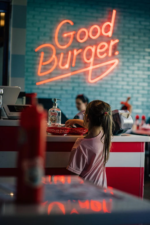 a  sitting at a diner counter in a restaurant with neon signs