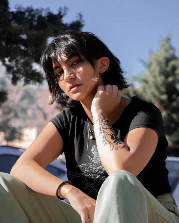 woman sitting down outside with a wrist tattoo