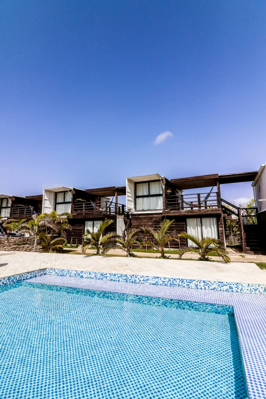 an empty swimming pool surrounded by wooden resort chairs