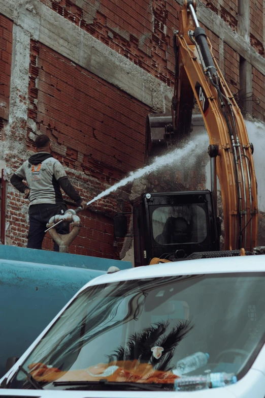 the street worker sprays his truck with a water hose