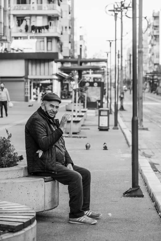 the man is sitting on a bench near a traffic light and pigeons