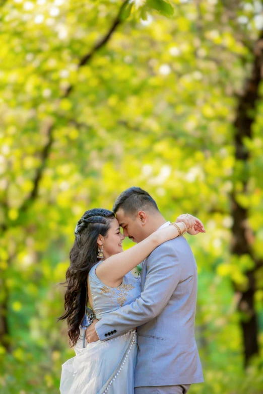 a couple are emcing each other in the middle of trees