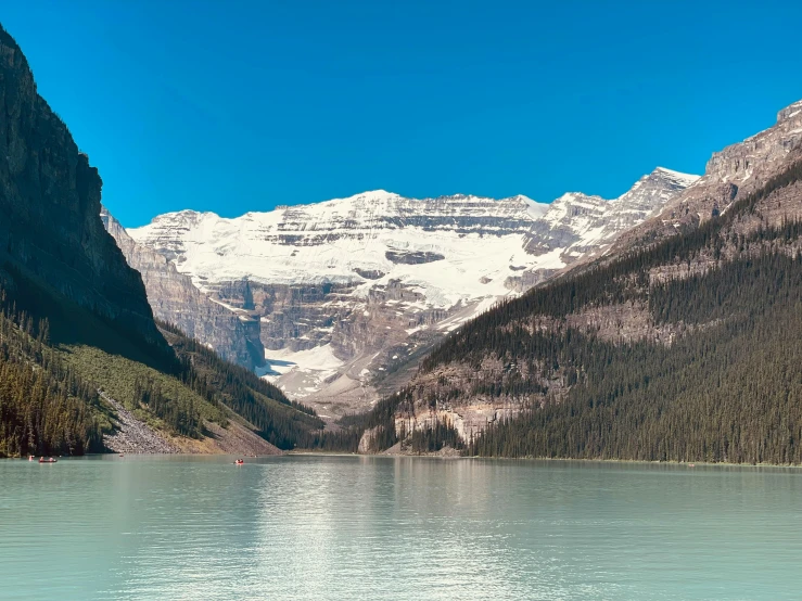 the trees and bushes are growing next to a mountain lake