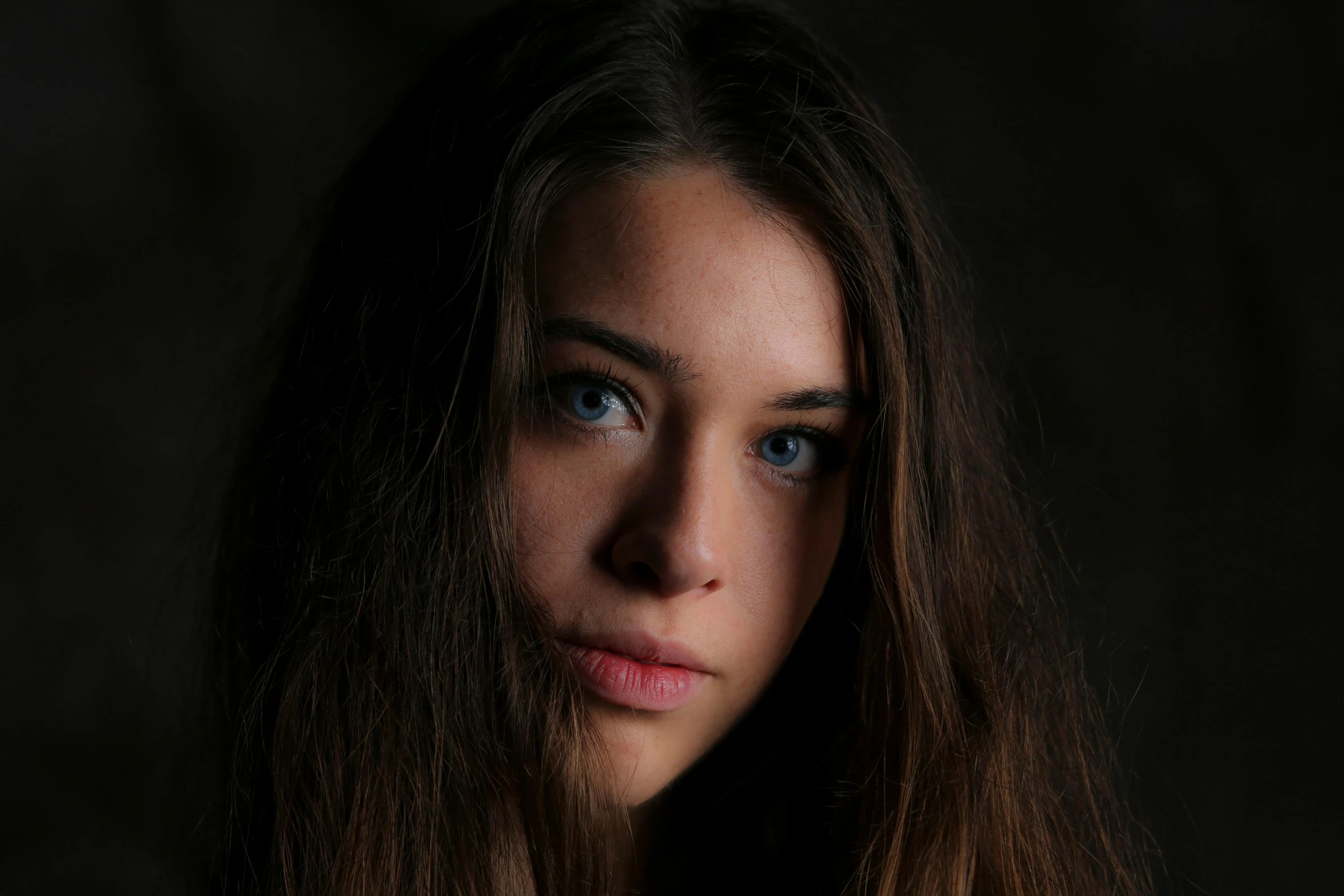 a girl's blue eyes and long hair looks towards the side