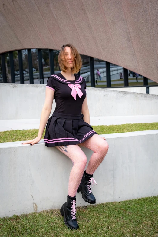 a woman sitting on a cement ledge with a pink ribbon