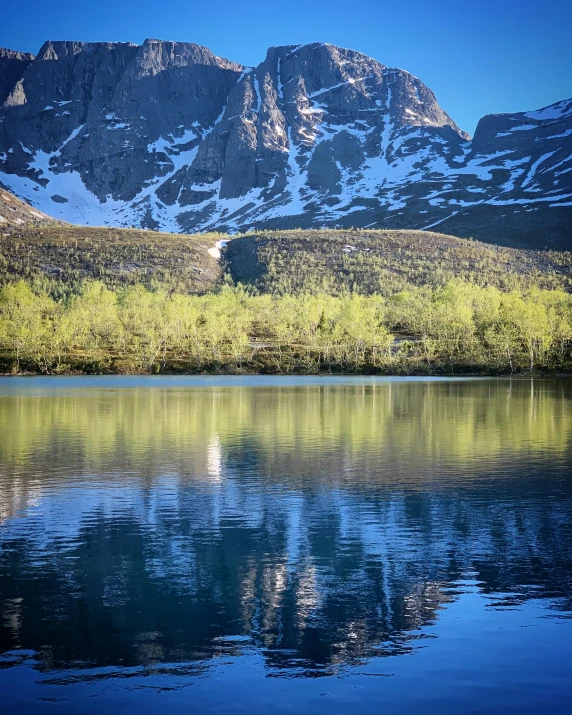 a mountain range covered in snow near a lake