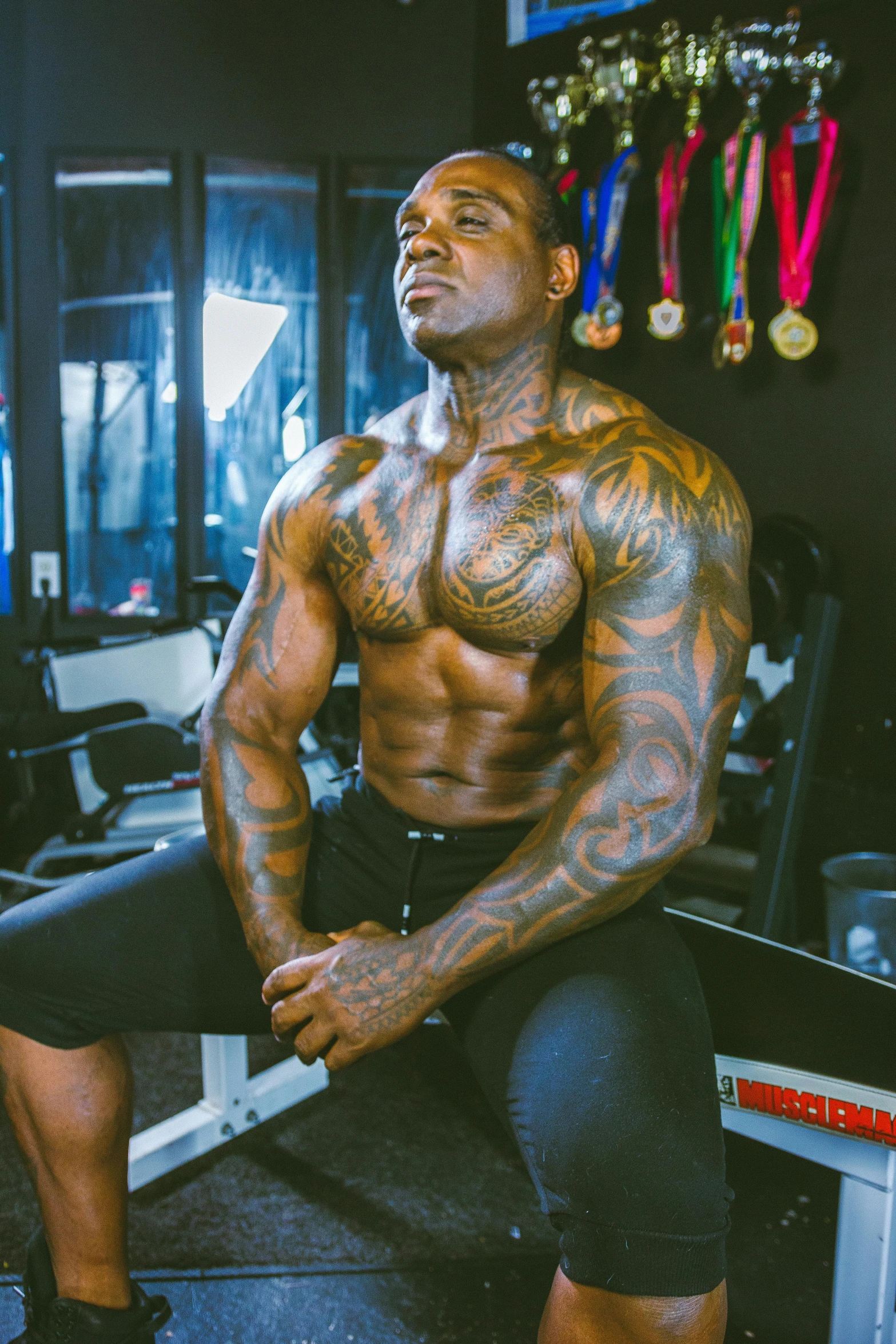 man sitting in a gym machine and showing off his big muscular body