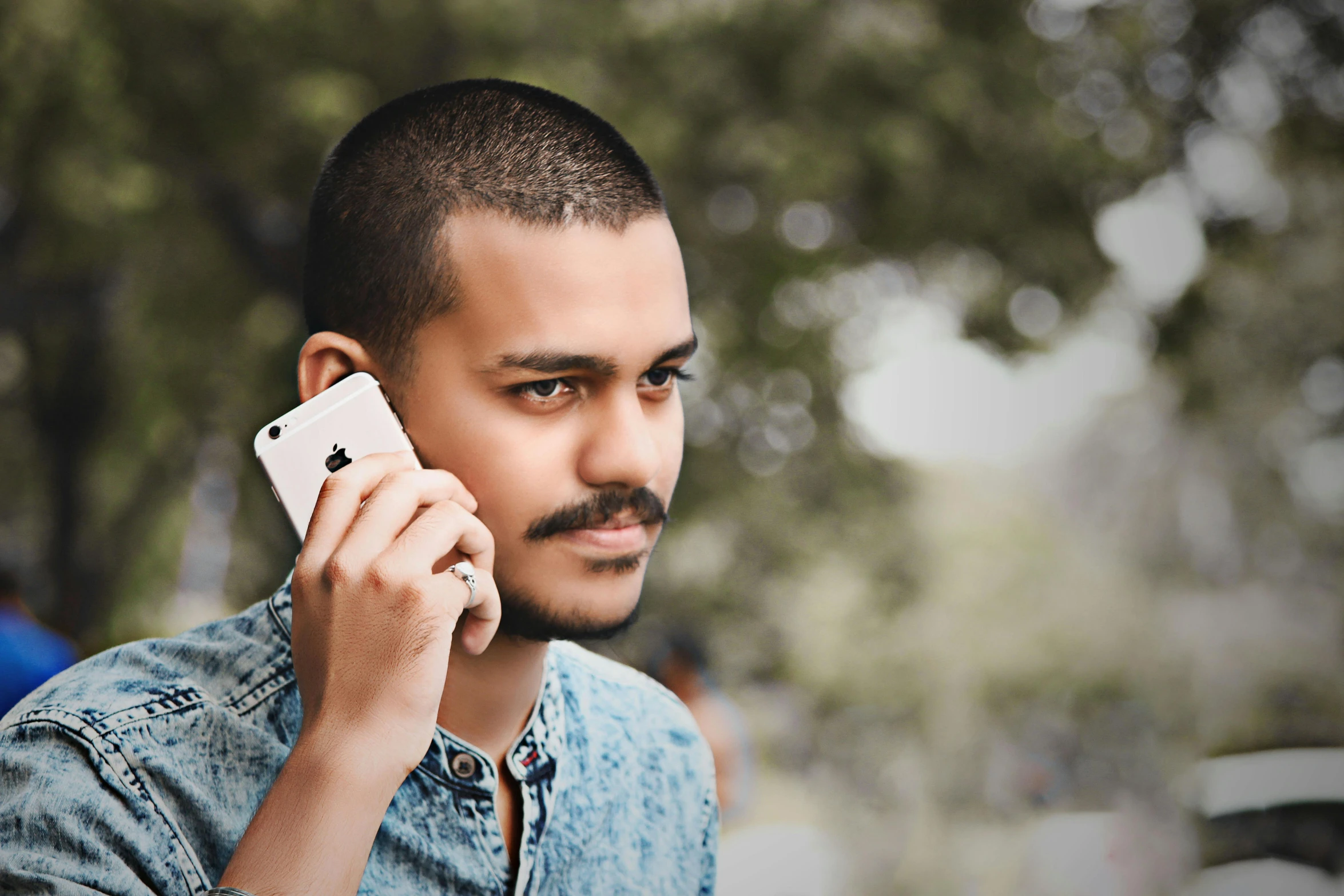 man talking on a cellphone with tree in the background