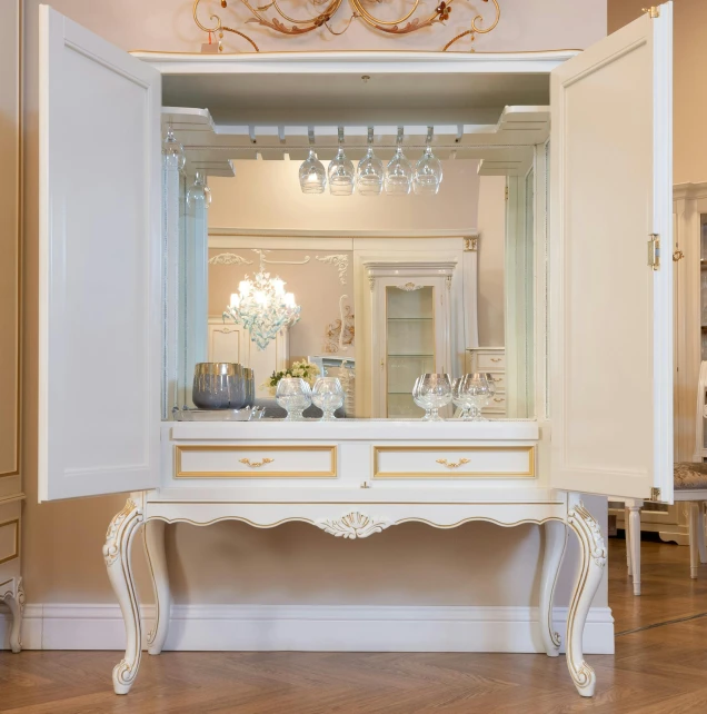 a white dresser with ornate detailing and chandelier