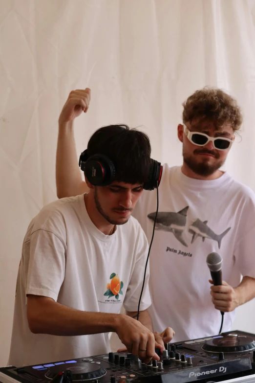 a man is dj and a man with headphones are mixing in front of a dj mixer