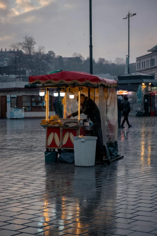 a street vendor stands in the rain with his ware