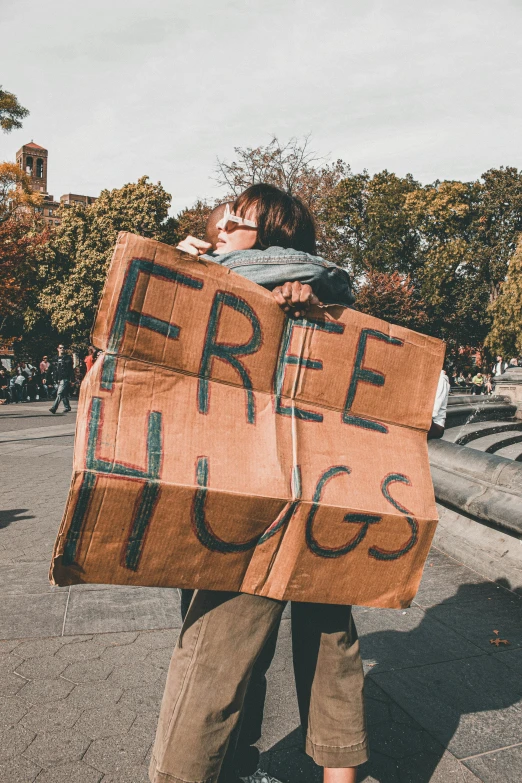 a man holding two large cardboard signs reading free hugs