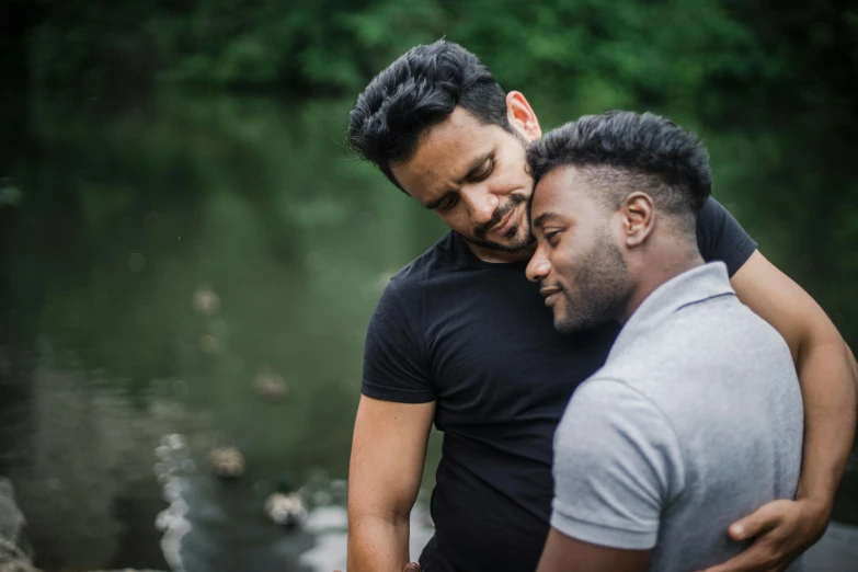 two men emcing each other in front of a river