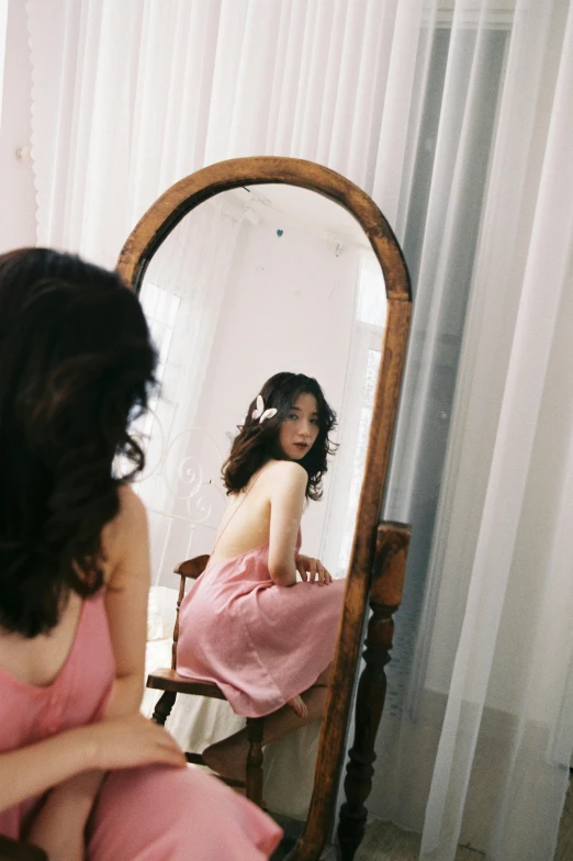 a woman in pink sitting in front of a mirror
