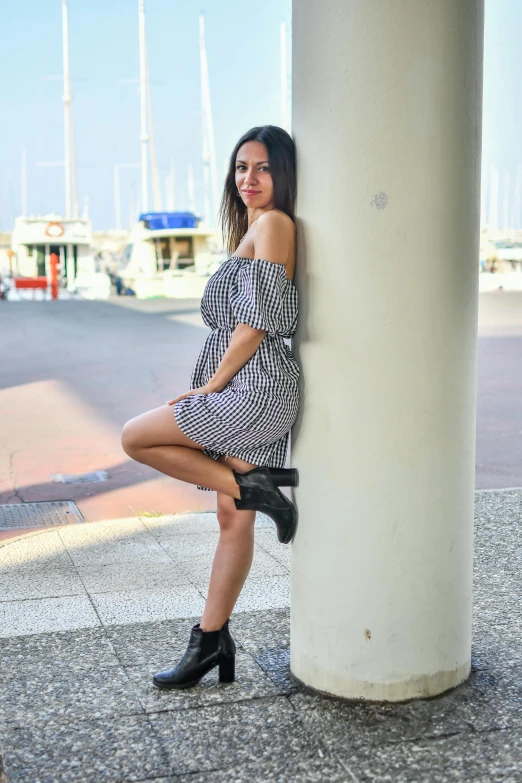 a woman is leaning against a column posing