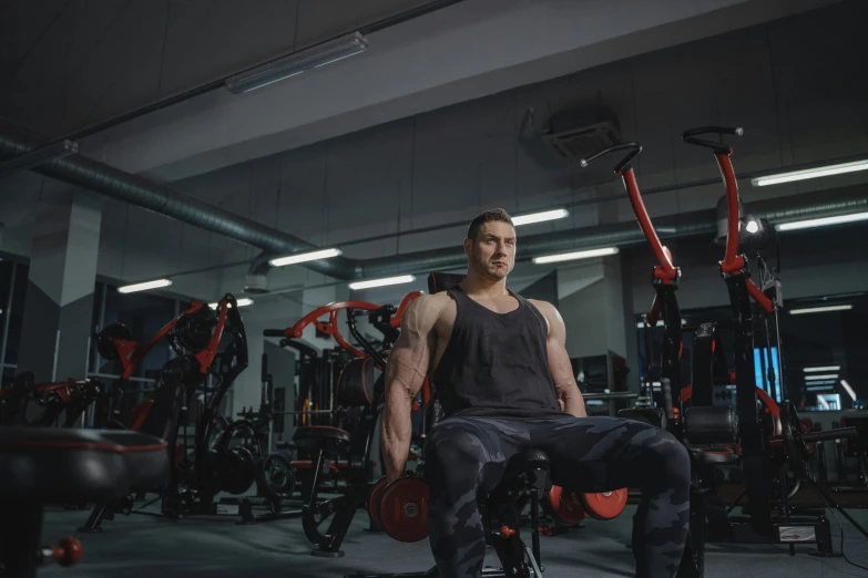 a young man sitting in a gym with the weight machine on his back