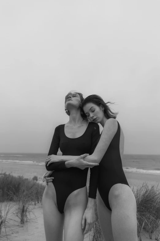 two women in bathing suits posing on the beach