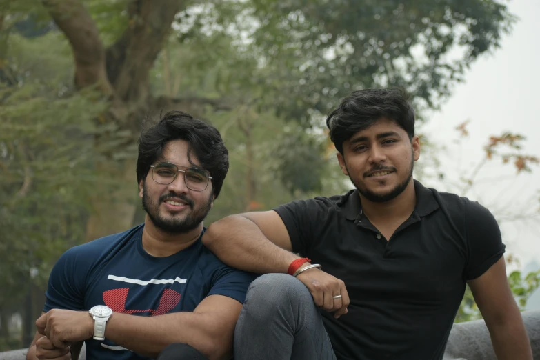 two men sitting on top of a black couch next to each other