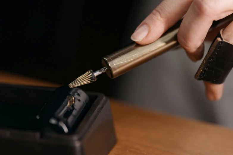 hand holding a pen with gold finish point and black ink