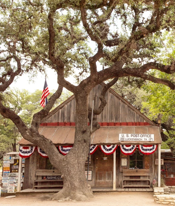 an old time country store with a tree and a flag