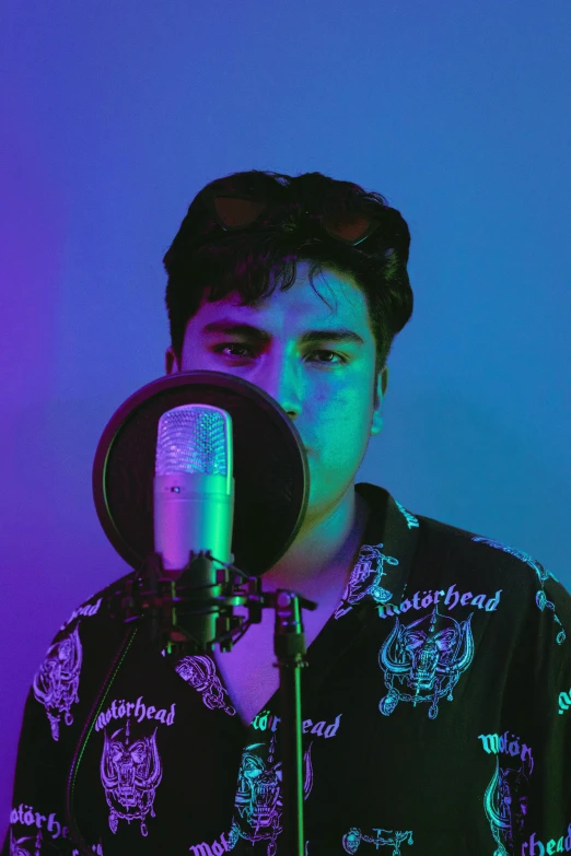 a man holding a microphone in front of a purple and blue background