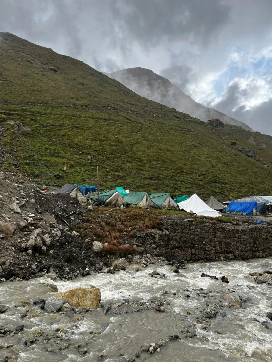 tents set up along a river next to a mountain