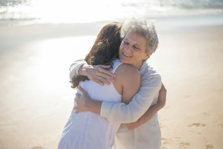 a woman hugs another woman on the beach