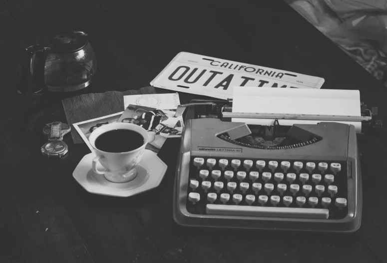 a desk topped with a coffee cup and an old typewriter