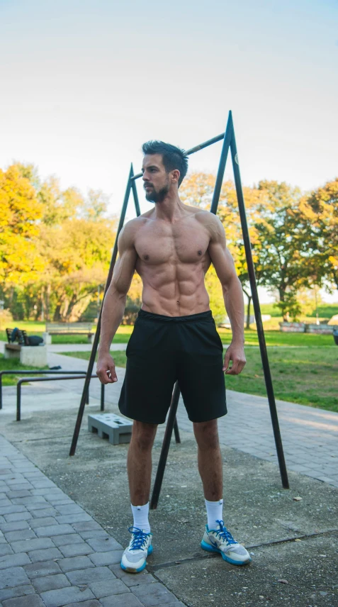 a male is posing for the camera in front of a swing set