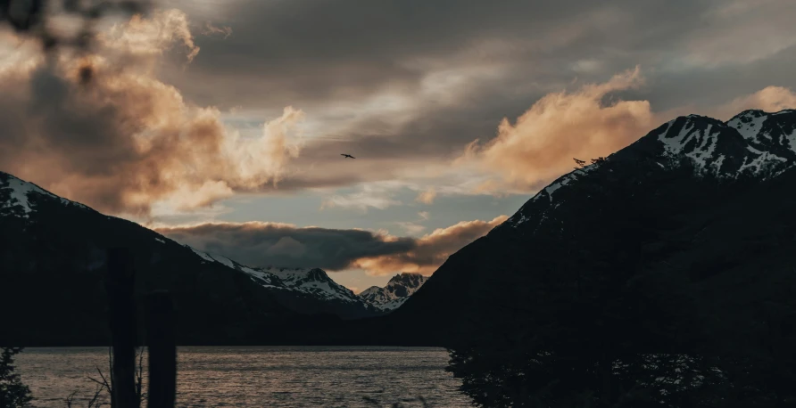 the sun is setting over mountains and water