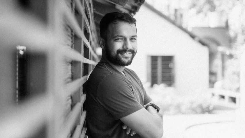 a black and white po of a smiling man leaning against a wall