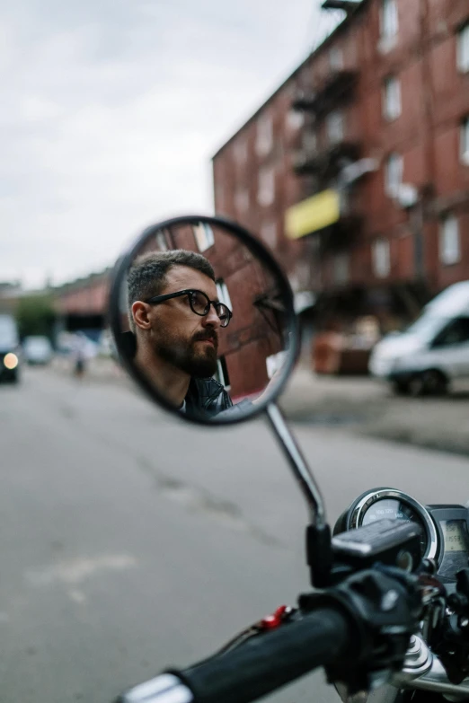 a man's face is reflected in the side mirror of a motorcycle