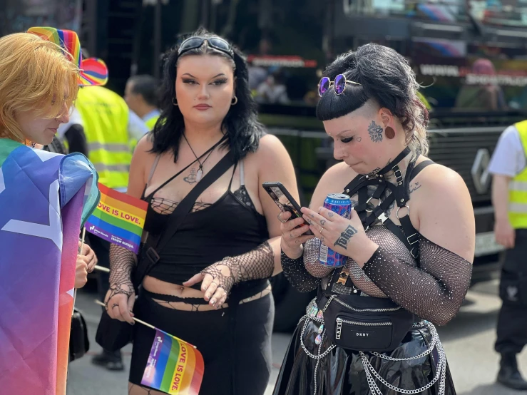 two women standing by each other while using their cell phones